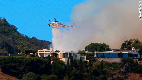 A helicopter makes a water drop as flames threaten homes on a ridgeline in the Pacific Palisades area of Los Angeles.