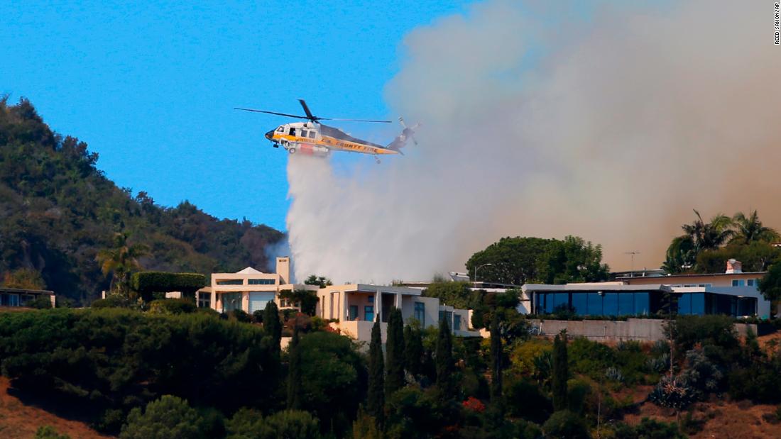 A helicopter makes a water drop in the Pacific Palisades area of Los Angeles.