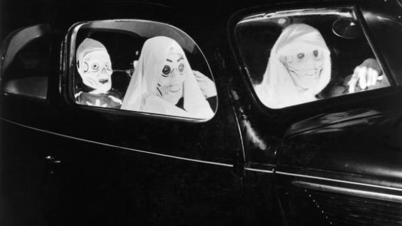  A 1938 image shows three people driving to a party in hair-raising skull masks.