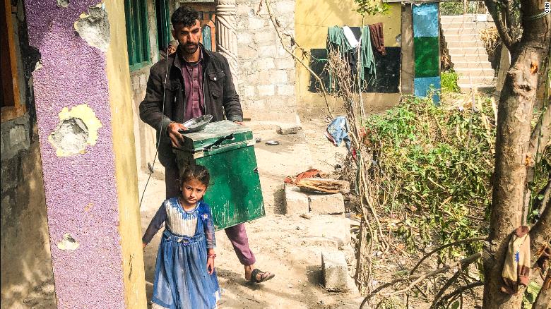 A little girl stands by her father as he clears rubbish in Jura, Neelum Valley, in Pakistani-administered Kashmir, on October 22, 2019. 