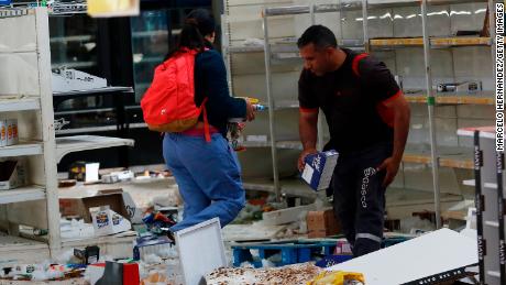 People take items from a looted supermarket in Santiago.