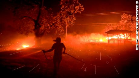 Susi Weaver, the manager for a ranch in the Mayacamas Mountains above Geyserville, California, sprays down the dry brush as the Kincade fire burns nearby on Thursday. 