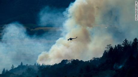 A helicopter passes a smoke plume as the Kincade Fire burns in Sonoma County. 