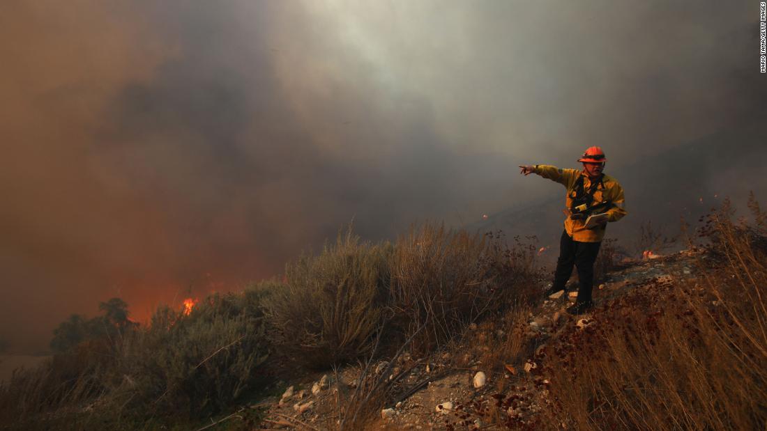 A Los Angeles County firefighter monitors the area as the Tick Fire burns near homes in Canyon Country on October 24.