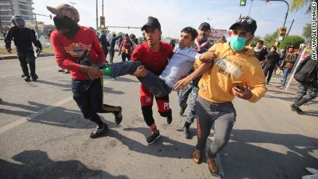 Iraqis carry a wounded demonstrator after security forces fired tear gas to disperse anti-government protests in Baghdad on October 25.