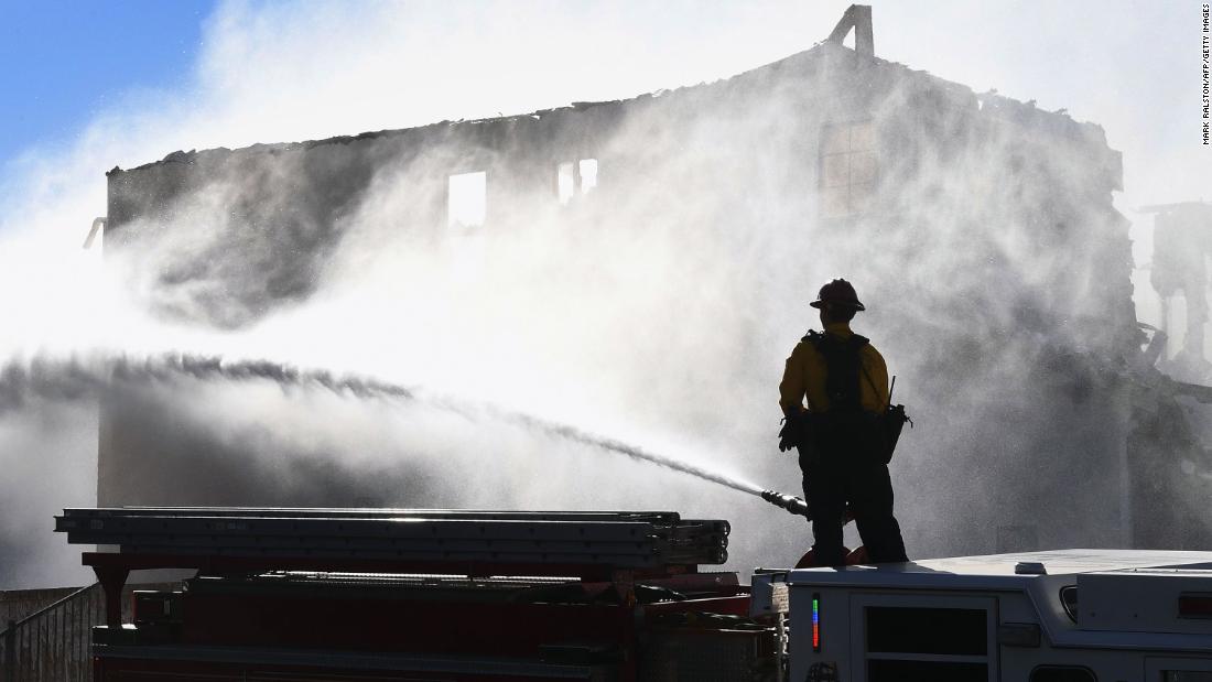 Firefighters hose down a burning house in Agua Dulce, California, on Friday, October 25. It was affected by the Tick Fire, which broke out near Santa Clarita.