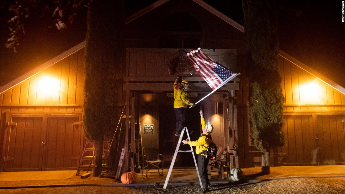 Firefighters from the Dry Creek Rancheria remove an American flag in Healdsburg.