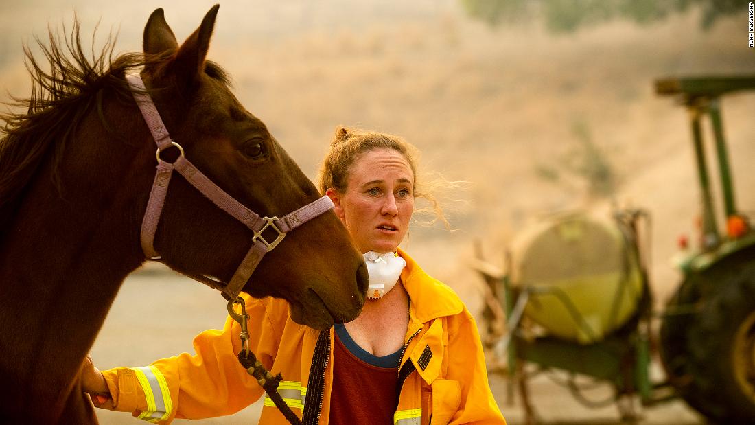 Dr. Emily Putt, a veterinarian who helps rescue horses from fire zones, comforts a horse as the Kincade Fire burns in Healdsburg on October 27.