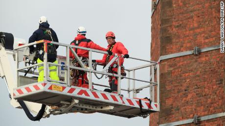 Members of Lancashire Fire and Rescue Service use a hydraulic platform at Dixon&#39;s Chimney in Carlisle, England, where a man was hanging upside down from the top of the 270-foot chimney.