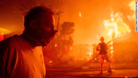 A man walks past a burning home during the Getty fire.