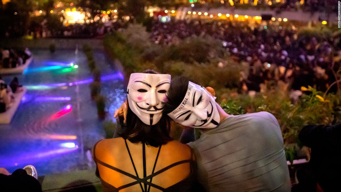 A couple wearing Guy Fawkes masks watch a rally at Chater Garden in Hong Kong on October 26.