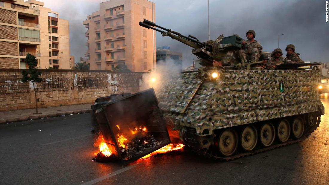 An armored personnel carrier removes a burning garbage container set alight by anti-government protesters on Monday, October 28.