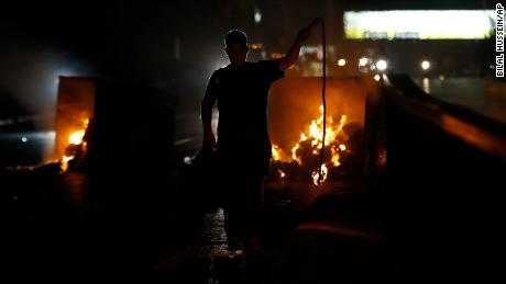 A supporter of Lebanese Prime Minister Saad Hariri burns garbage containers to block a main road in Beirut, Lebanon, Tuesday, Oct. 29, 2019.