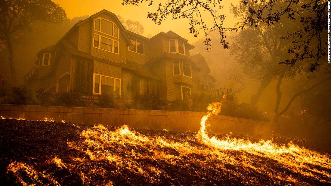 Firefighters burn fuel around a home in Windsor in an effort to save it from the Kincade Fire.