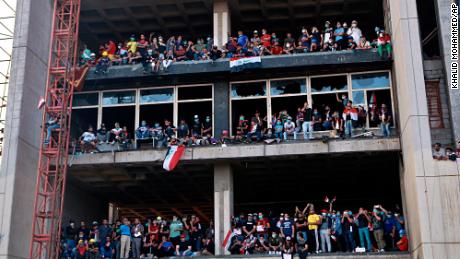 Anti-government protesters stand on a building near Tahrir Square during protests in Baghdad on October 30.