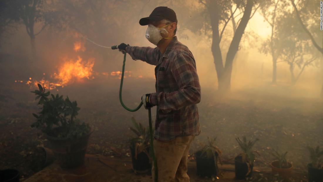 Marco Alcaraz uses a garden hose to try to slow down the advance of the Easy Fire in Simi Valley.