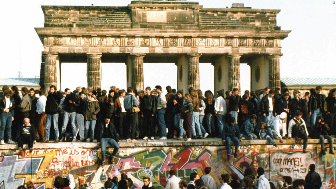 People walk on the Berlin Wall in front of the Brandenburg Gate on November 10, 1989. 