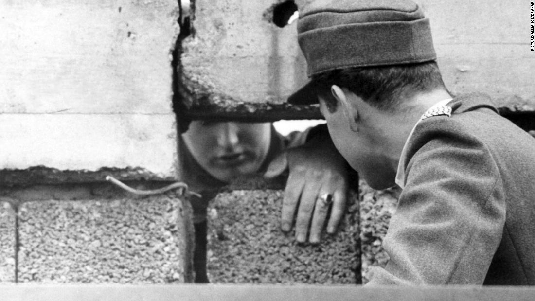 A guard from West Berlin (right) talks to an East Berliner through a hole in the Wall, September 1962. 