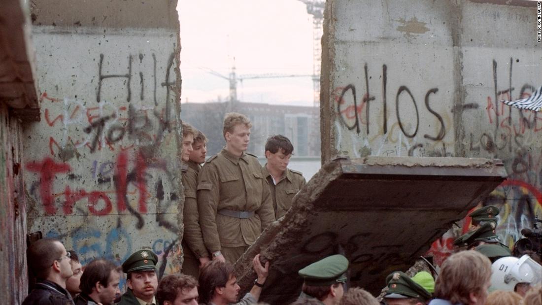 East German border guards appear in a gap in the Wall after demonstrators pulled down a segment of the barrier, on November 11, 1989. 