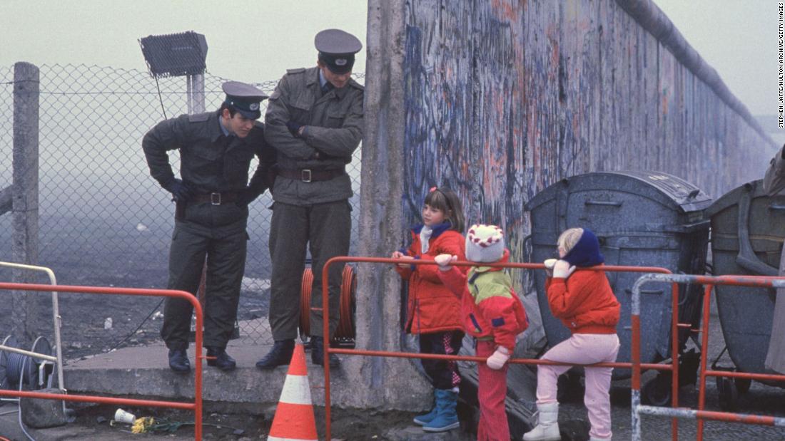 West German children interact with East German border guards after the fall of the Berlin Wall in 1989. 