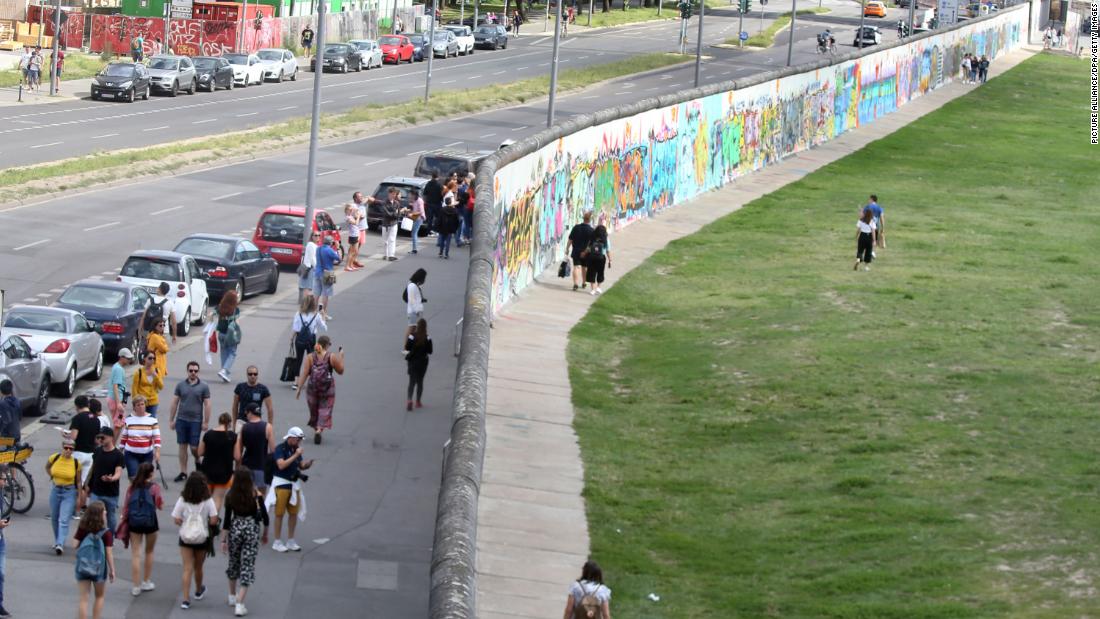 People walk along the longest remaining section of the Wall, now known as the East Side Gallery, in August this year. 