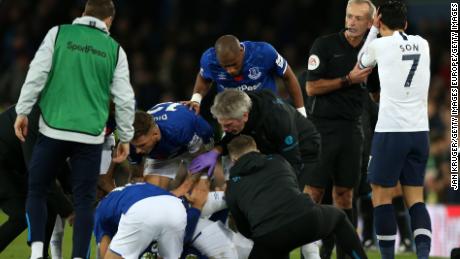 Match referee Martin Atkinson consoles Son Heung-Min as Everton players and medical staff cluster around the stricken Andre Gomes. 