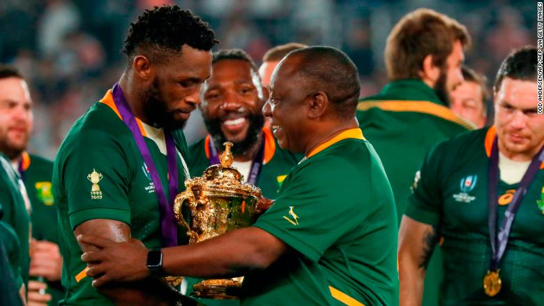 South Africa&#39;s President Cyril Ramaphosa (C) congratulates South Africa&#39;s flanker Siya Kolisi (L) as they celebrate winning the 2019 Rugby World Cup.