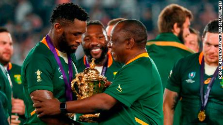 South Africa&#39;s President Cyril Ramaphosa (C) congratulates South Africa&#39;s flanker Siya Kolisi (L) as they celebrate winning the 2019 Rugby World Cup.