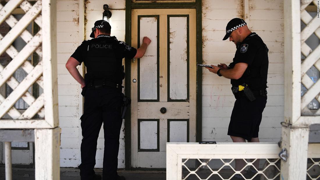 Police knock on the door of a house to warn residents of an out-of-control bushfire near Clumber on November 8. 