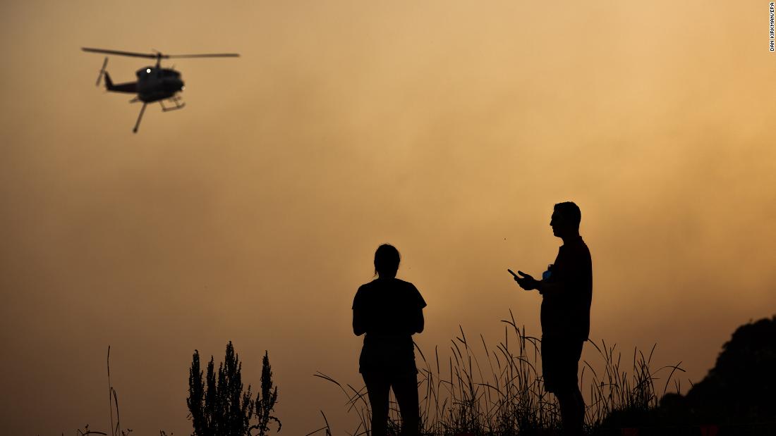 Forster residents watch as a water-bombing helicopter flies over a bushfire on November 7.