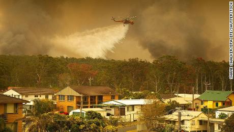 A water bombing helicopter drops water on a bushfires in Harrington, New South Wales, Australia, 08 November 2019.