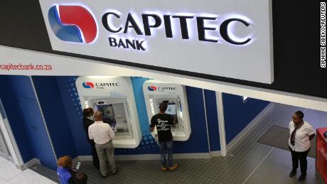 Customers draw money from an ATM outside a branch of Capitec Bank in Johannesburg.