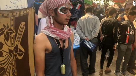 A protester in the tent city has painted the Iraqi flag on his face. He wears a tear gas canister as a medal to show he&#39;s not afraid.