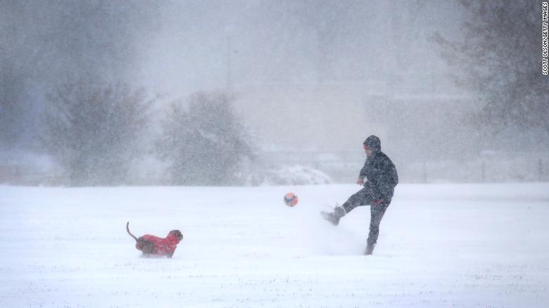 A resident plays with his dog as snow falls in Humboldt Park in Chicago.