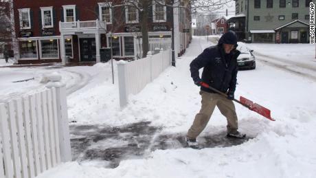 Bill Langley tries to clear a blanket of snow Tuesday from the Green Mountain Inn in Stowe, Vermont.