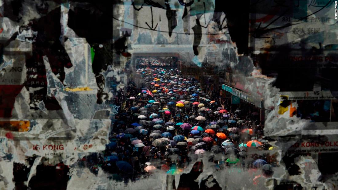 Marching anti-government protesters are seen through a window with peeled-off posters on October 1.