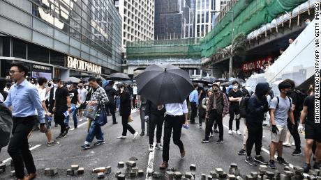 Office workers and pro-democracy protesters walk around bricks lying on a street during a demonstration in Central in Hong Kong on November 12, 2019.