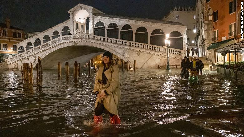 A tourist walks near the Rialto bridge after the passage of the exceptional high tide that reached 187 cm on November 12, 2019 in Venice, Italy. 