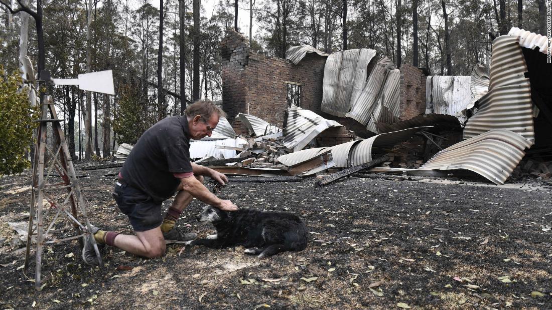 Warren Smith pats his dog after returning to find his house destroyed near Nana Glen on November 13.