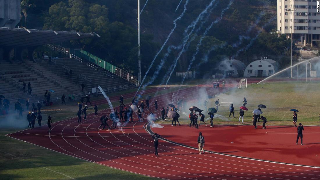 Students attempt to clear tear gas canisters fired by riot police onto a sports track during a confrontation at the Chinese University in Hong Kong on Tuesday, November 12.