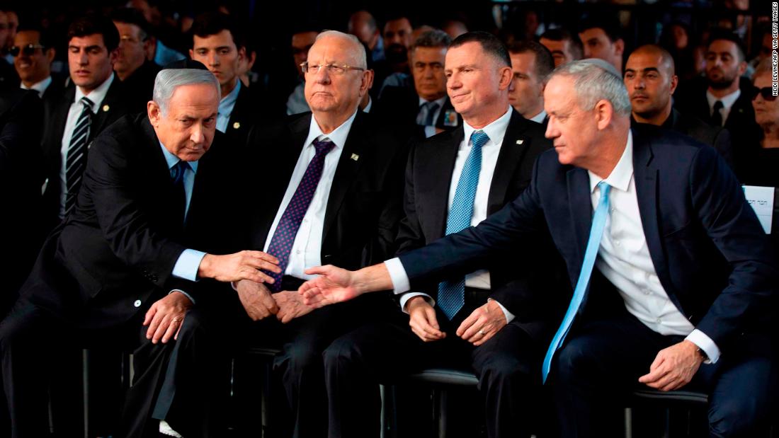Netanyahu and Israeli Blue and White party chief Benny Gantz reach to shake hands during a state memorial ceremony for former Israeli Prime Minister Yitzhak Rabin and his wife, Leah, in November 2019. Exit polls for a repeat general election failed to give either of the political rivals a majority in the new parliament.