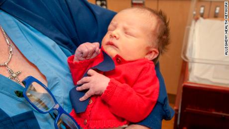 A baby at the West Penn Hospital is dressed up in a red cardigan and tie to celebrate World Kindness Day and Cardigan Day in honor of Mister Rogers.