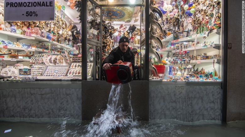 A shopkeeper throws out water from his shop during an exceptional high tide on November 13 in Venice.