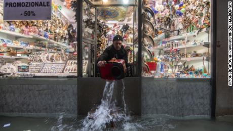 A shopkeeper throws out water from his shop during an exceptional high tide on November 13 in Venice.