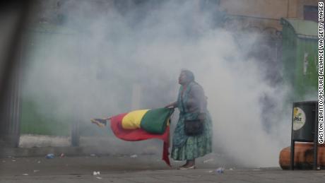 An indigenous protester is standing with a flag in tear gas smoke during Wednesday&#39;s unrest in La Paz.