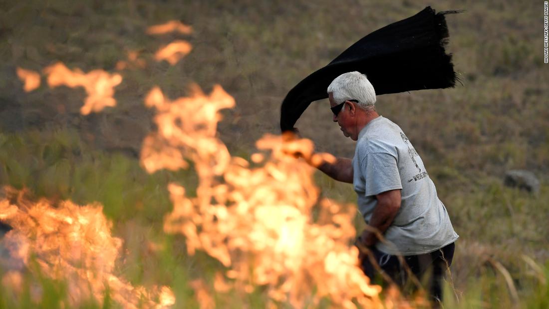 A man uses a wet towel to help put out flames near the town of Taree on November 14.