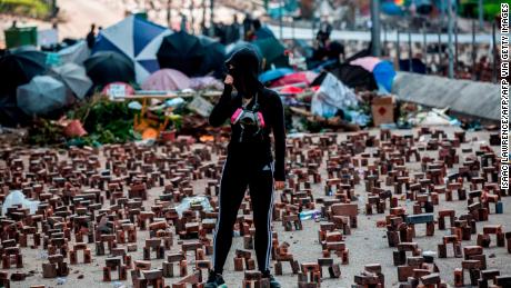 A protester (C) stands amongst bricks placed on a barricaded street outside The Hong Kong Polytechnic University in Hong Kong on November 15, 2019. 