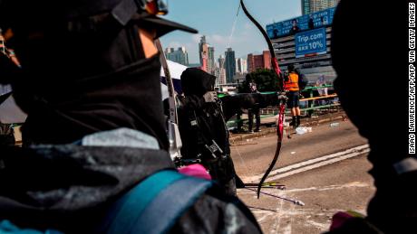 A protester uses a bow and arrow while standing on a barricaded street outside The Hong Kong Polytechnic University in Hong Kong on November 15, 2019. 