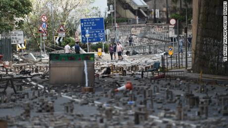 People walk on Saturday, November 16, among bricks laid on a road by protesters near a university in Hong Kong.