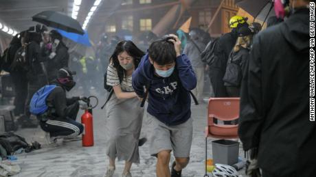 TOPSHOT - Protesters run for cover after riot police fired tear gas towards the bridge they attempt to climb down to the road below, to escape from Hong Kong Polytechnic University campus and from police, in Hung Hom district in Hong Kong on November 18, 2019. - Dozens of Hong Kong protesters escaped a besieged university campus on November 18 by lowering themselves on a rope from a footbridge to a highway, AFP video showed. Once on the road they were seen being picked up by waiting motorcyclists. (Photo by Anthony WALLACE / AFP) (Photo by ANTHONY WALLACE/AFP via Getty Images)